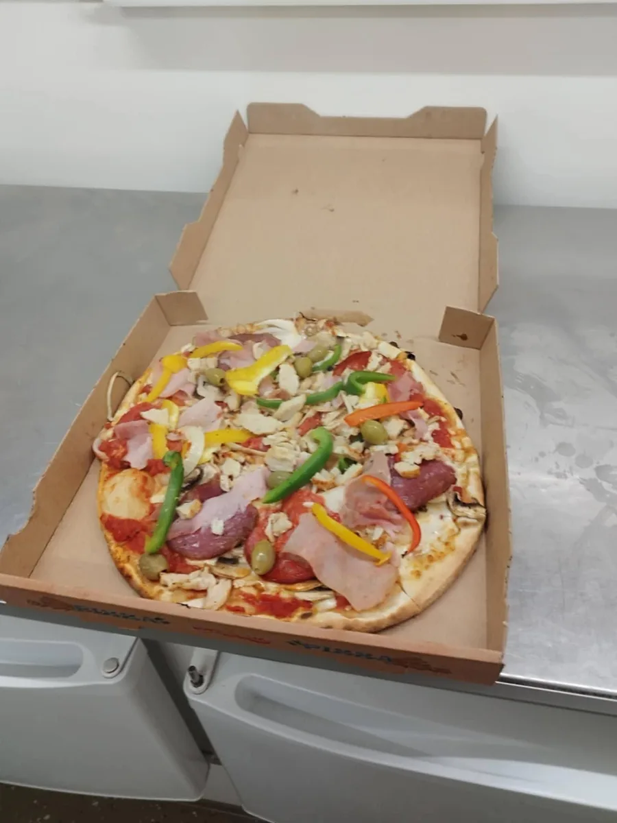 Pizza gourmande garnie de jambon, salami, poivrons et olives