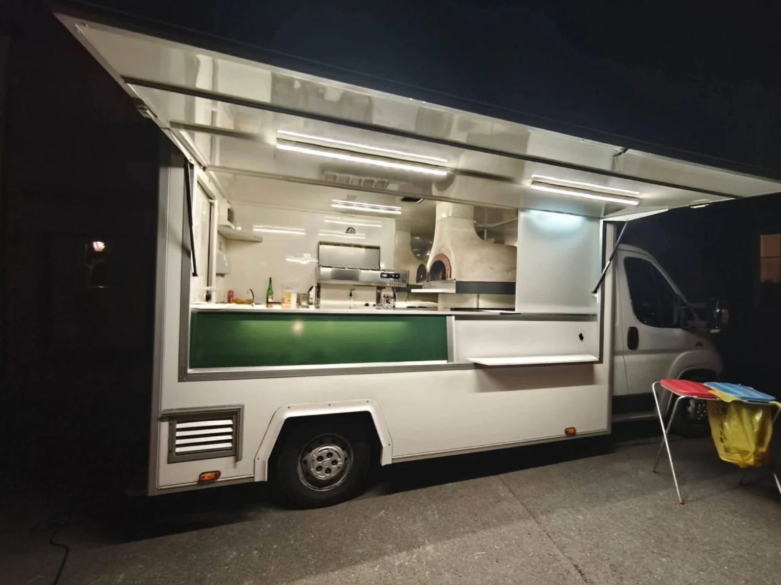 Le camion de la Pizza Gourmande de nuit, hayon ouvert, four à bois visible à l'intérieur
