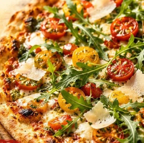 Pizza Vegan : base tomates et fromage végan, garnie de roquette, tomates cerises et pesto